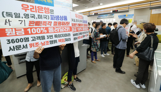 우리은행이 판매한 해외금리 연계 파생결합펀드(DLF)의 만기일인 19일 오전 경기도 성남시 우리은행 위례신도시점으로 투자 피해자들이 방문해 항의하고 있다. <연합뉴스>